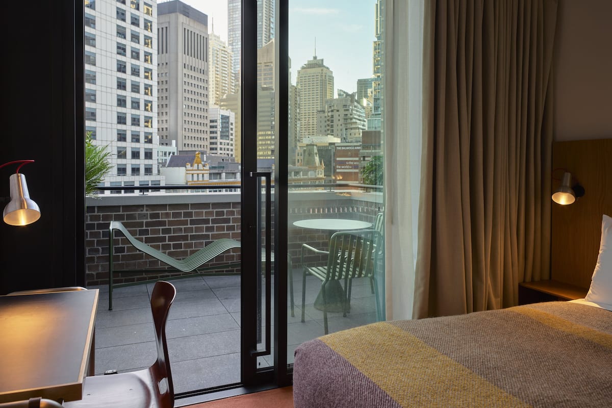 A hotel room with a balcony, a bed, a table, and chairs.