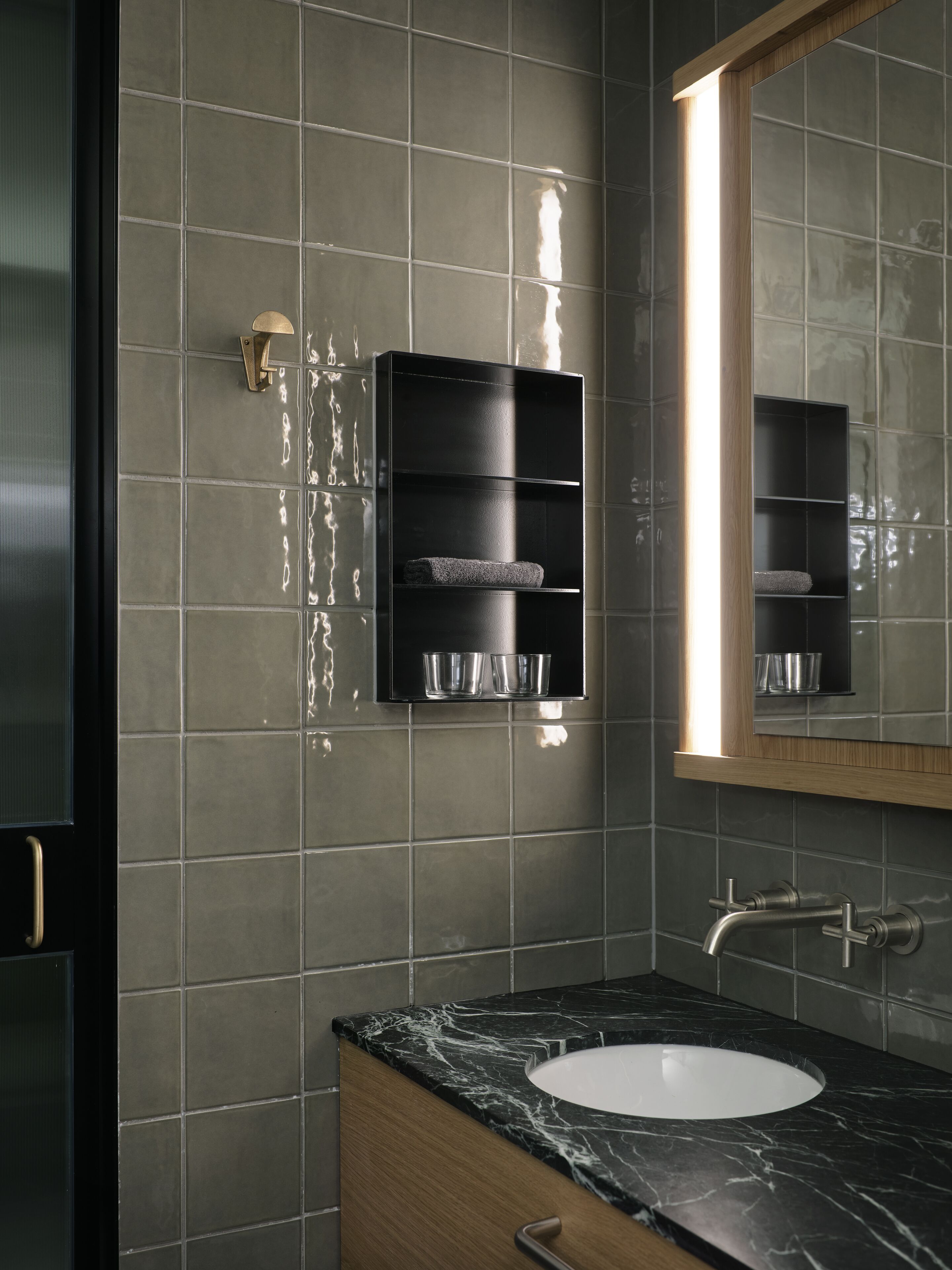 A bathroom with a black marble sink, a mirror, and a towel rack.