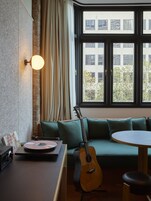Una habitación con un sofá verde, una guitarra, un tocadiscos y una mesa con una lámpara.
