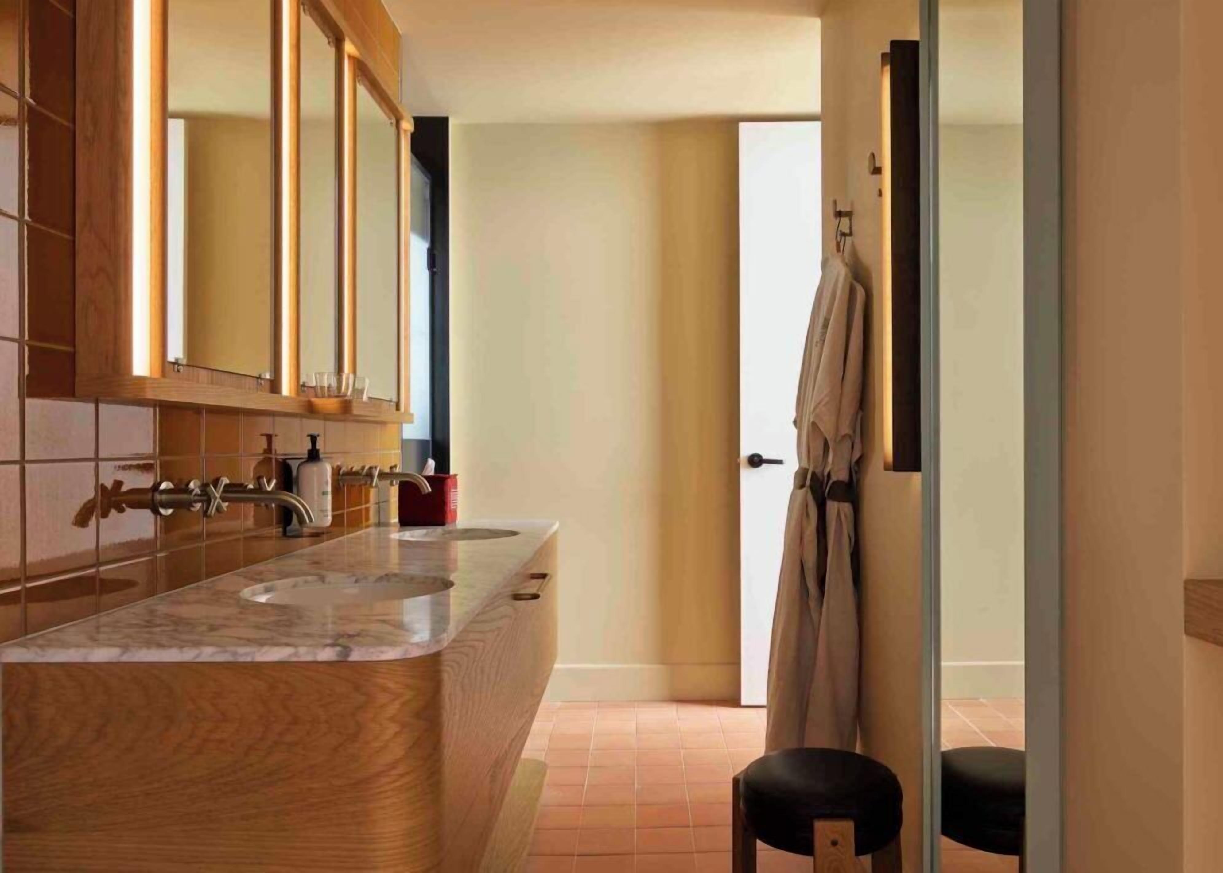 A modern bathroom with a wooden vanity, a large mirror, and a towel rack.