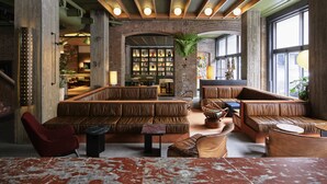 A spacious lounge with leather seating, a brick wall, and a large bookshelf. - Ace Hotel Sydney (Sydney)