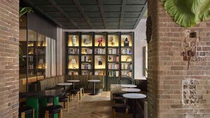 A cozy reading nook with bookshelves, leather seating, and a brick archway. - Ace Hotel Sydney (Sydney)