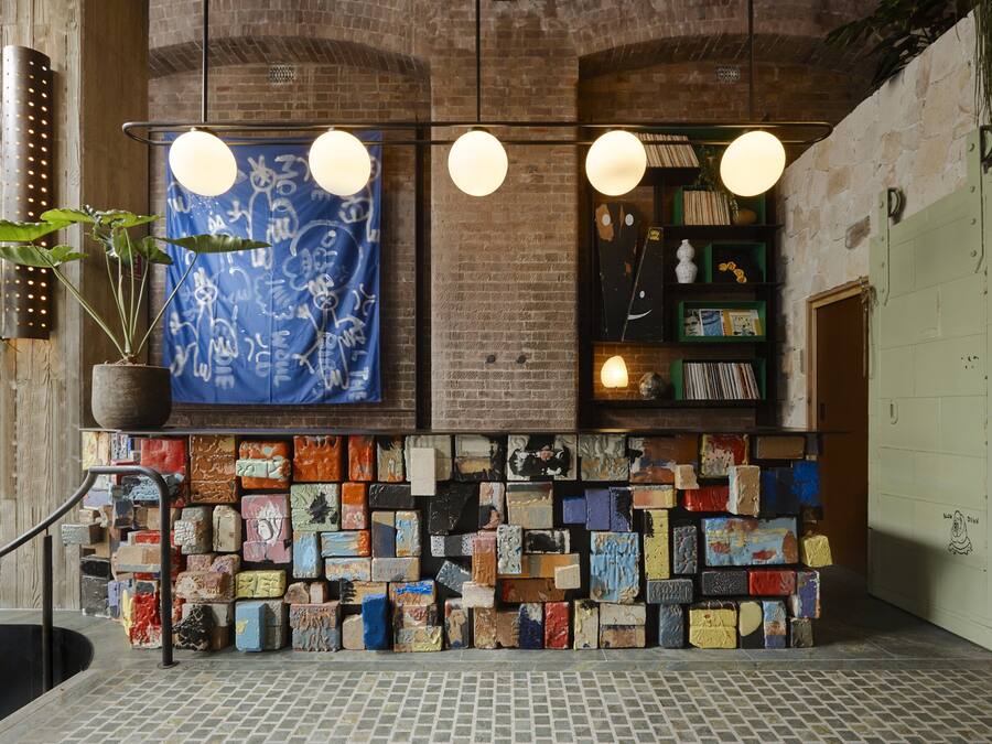 Eine Wand mit bunten Fliesen, ein blaues Musterbanner und ein Regal mit Büchern und Dekoration.