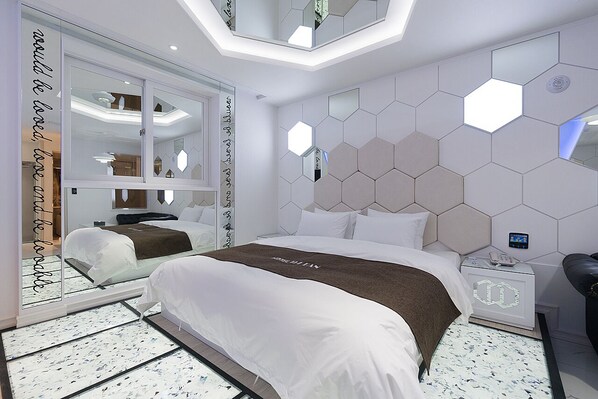 A modern hotel room with a large bed, a nightstand, and a mirror. - Theban Hotel (Chungju)