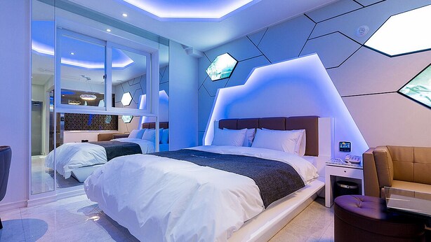 A modern hotel room with a large bed, a desk, and a seating area. - Theban Hotel (Chungju)