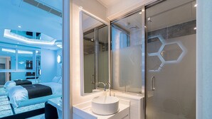 A modern bathroom with a glass shower enclosure, a white sink, and a large mirror. - Theban Hotel (Chungju)