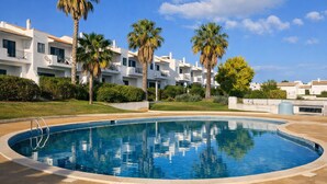 A swimming pool with a clear blue water surface, surrounded by a tiled deck.