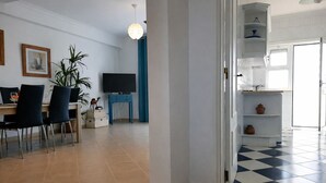 A modern living room with a dining area, a flat-screen TV, and a blue accent wall.
