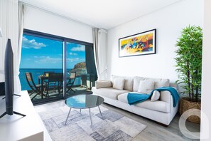 En moderne stue med sofa, sofabord og havudsigt.