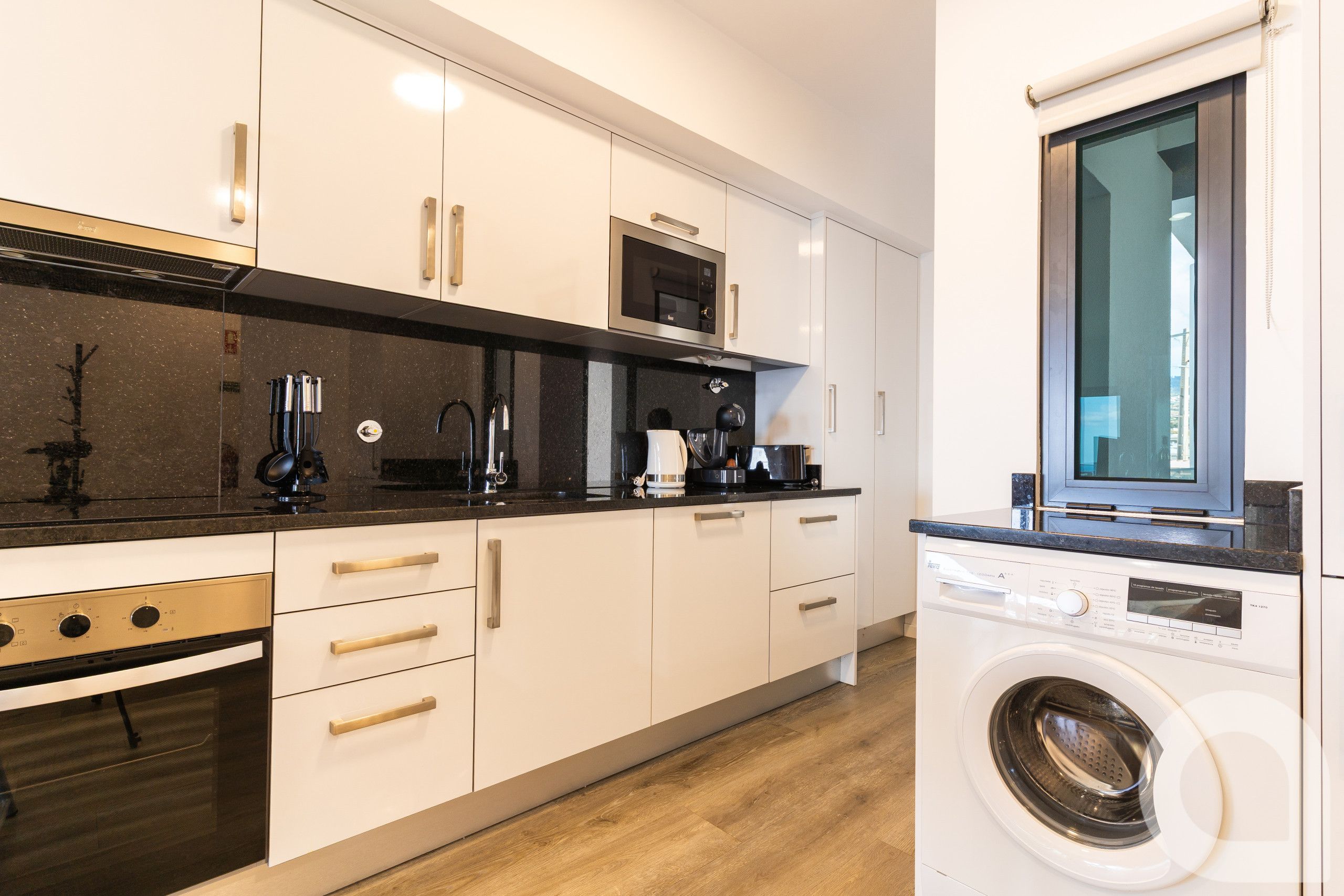 A modern kitchen with a built-in oven, microwave, and coffee maker.