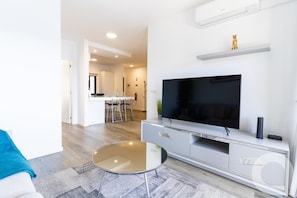 A modern living room with a flat-screen TV, a glass coffee table, and a minimalist design. - Belle Vue Résidence by Atlantic Holiday (Gaula)