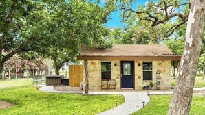 A small stone house with a dark blue door, a front porch, and a pathway leading to it.