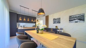 Une cuisine moderne avec des meubles de couleur sombre, un îlot central et des luminaires suspendus.