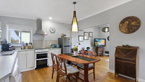 Une cuisine moderne avec des meubles blancs, une table à manger en bois et un luminaire suspendu.