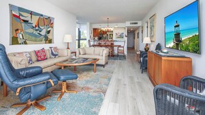 A spacious living room with a sofa, chairs, a coffee table, and a dining area with a kitchen in the background.