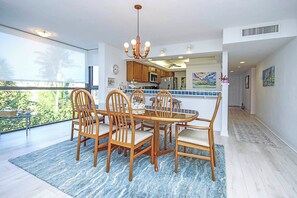 A dining area with a round table and chairs, a chandelier, and a view of the outdoors. - Snug Harbor 124 Gulf Front three bedroom exclusive vacation rental (Sanibel)