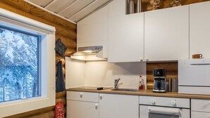 Et moderne køkken med lyse skabe, en stålvask, kaffemaskine og et indbygget ovn.