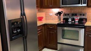 Una cucina con mobili in legno, un frigorifero in acciaio inossidabile, un forno a microonde e un forno.