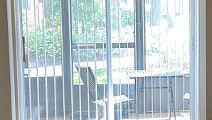 Una stanza con una porta scorrevole in vetro che dà su un balcone con tavolo e sedie.