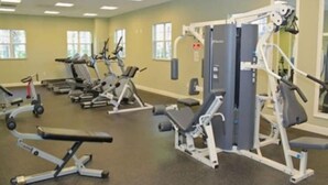Una palestra con diverse macchine per esercizi, una panca per pesi e un rastrello per manubri.