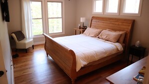 Ein Schlafzimmer mit einem Holzbett, einem Sessel, einem Nachttisch und einem Deckenventilator.