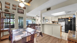 A spacious kitchen with a central island, a dining area with a table and chairs, and a view to the outside.