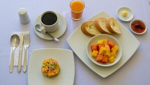 A breakfast setting with a plate of scrambled eggs, toast, and fruit, a cup of coffee, a glass of orange juice, and condiments. - Stay Villa Marta (Cartagena)