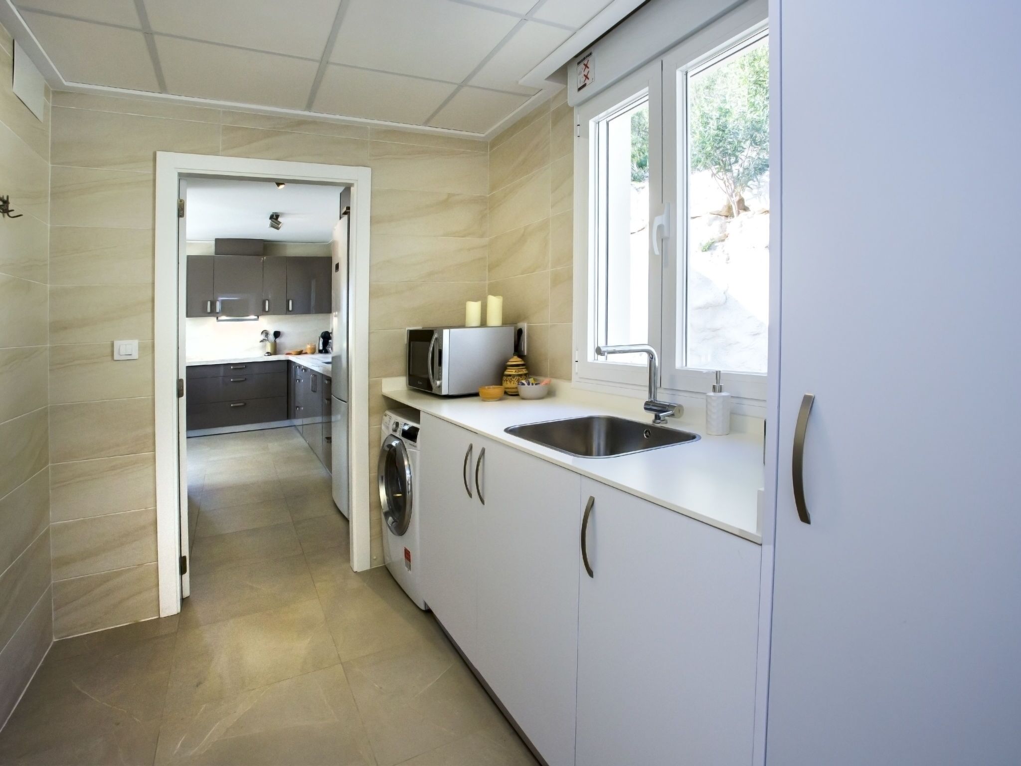 A modern kitchen with white cabinets, a stainless steel sink, and a microwave.