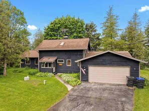 A two-story house with a garage, a small porch, and a well-maintained lawn.