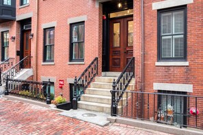 Classic brick building with a traditional design, featuring a set of stairs and a wooden door.