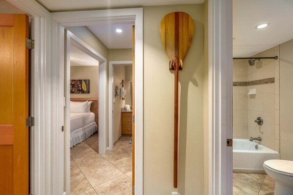 A hotel room with a wooden paddle, a bed, a bathroom with a bathtub, and a shower.