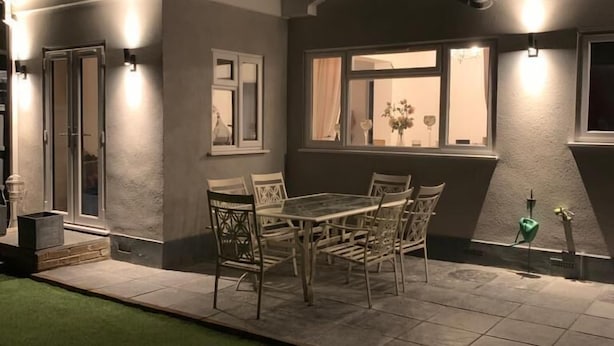 A modern house with a patio, outdoor furniture, and a statue.