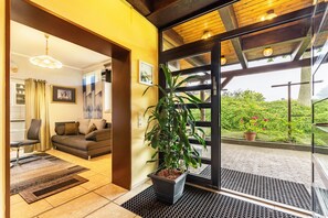 Un salon moderne avec un canapé, une plante en pot et une vue sur la verdure à l’extérieur.