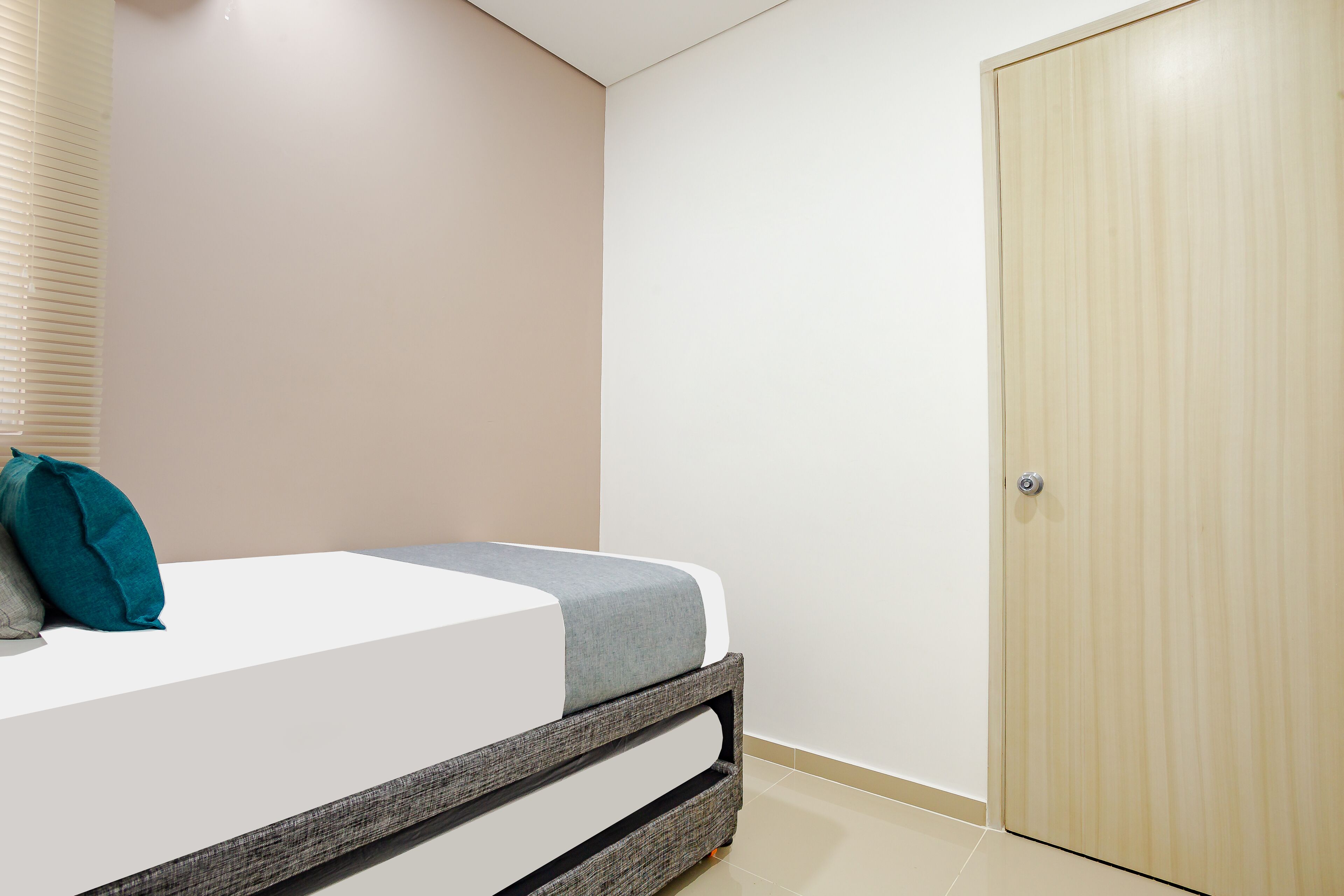 Un dormitorio con una cama, una puerta y una ventana con persianas.