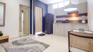 A modern kitchen with a refrigerator, wooden cabinets, and a dining area with a table and chairs. - Montepinares Apartaestudios (Montería)
