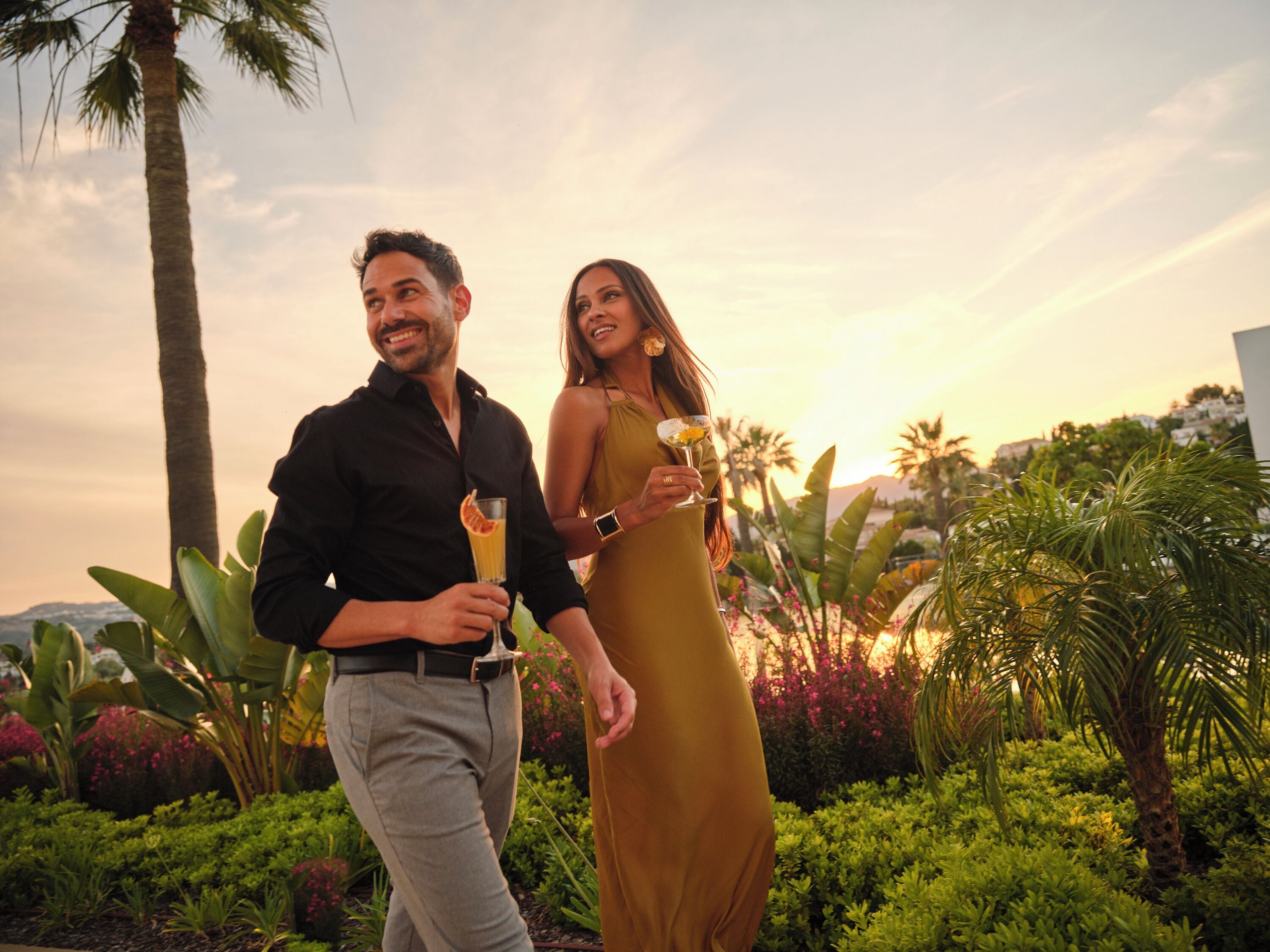 A couple standing outdoors with a sunset in the background.