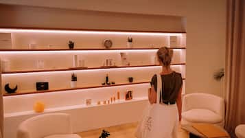 Un interior moderno con un mostrador de recepción, sillas blancas y estanterías con distintos objetos.