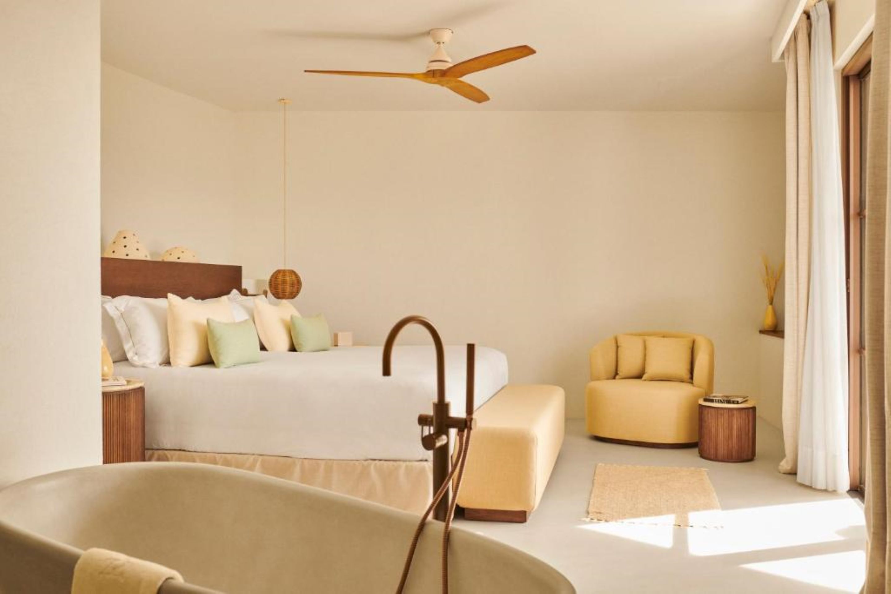 A modern bedroom with a large bed, a bathtub, a ceiling fan, and a sofa.