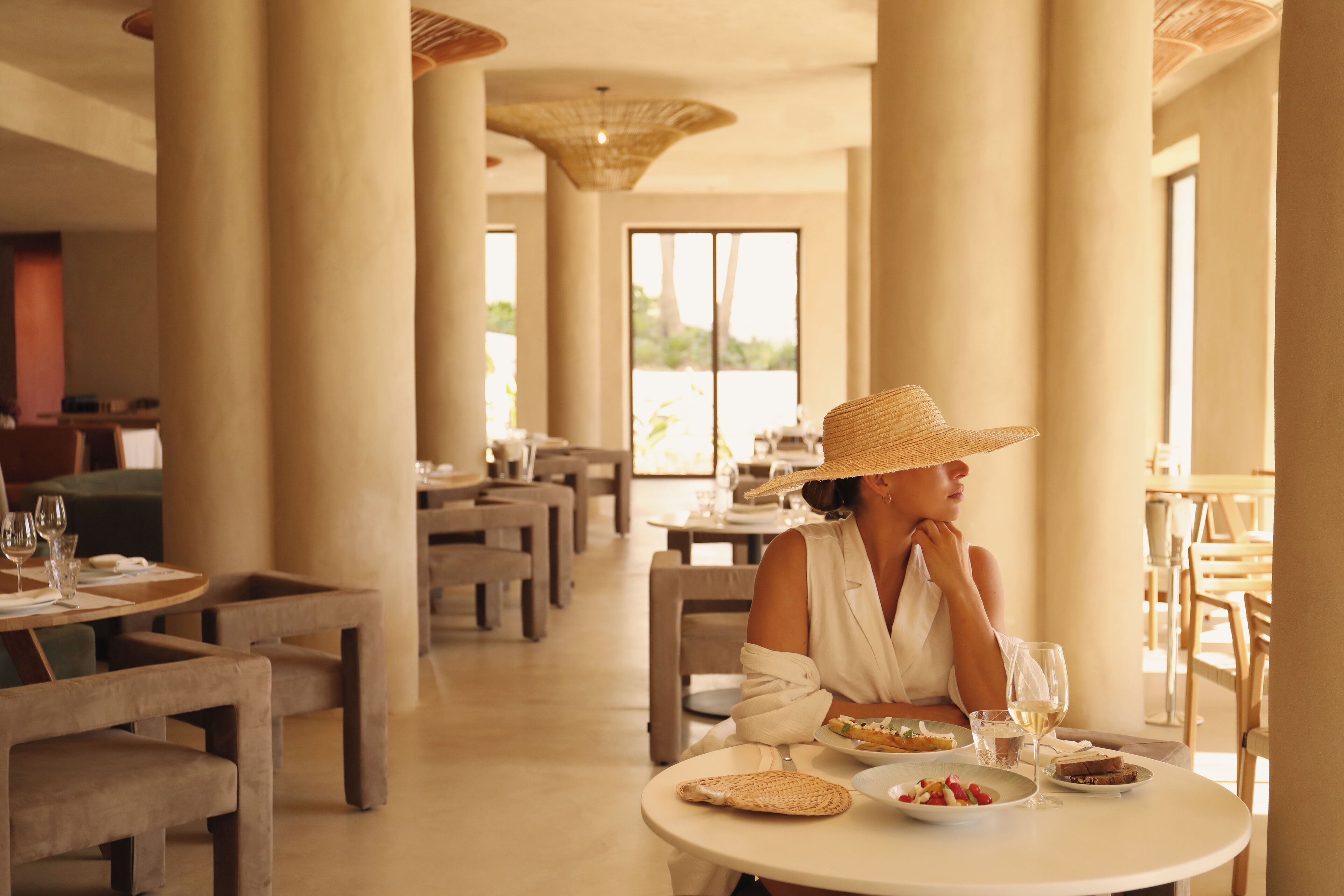A dining area with round tables, chairs, and a large window with a view.