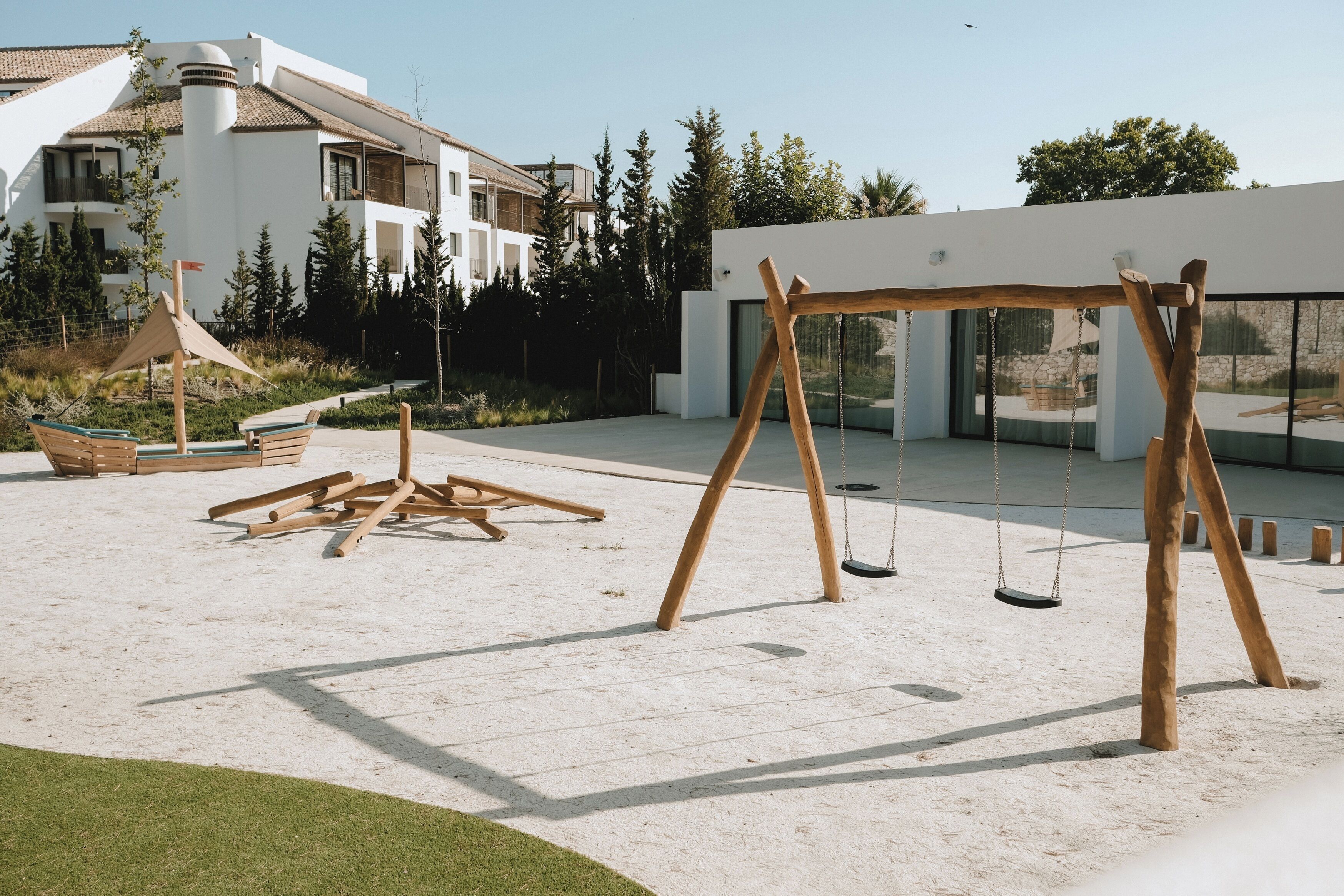 A modern outdoor area with a swing set, a wooden bench, and a small table.