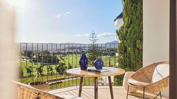 A balcony with a round table, two blue vases, a potted plant, and a wicker chair.