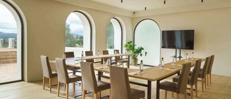 A conference room with a long table, chairs, a TV, and large windows.