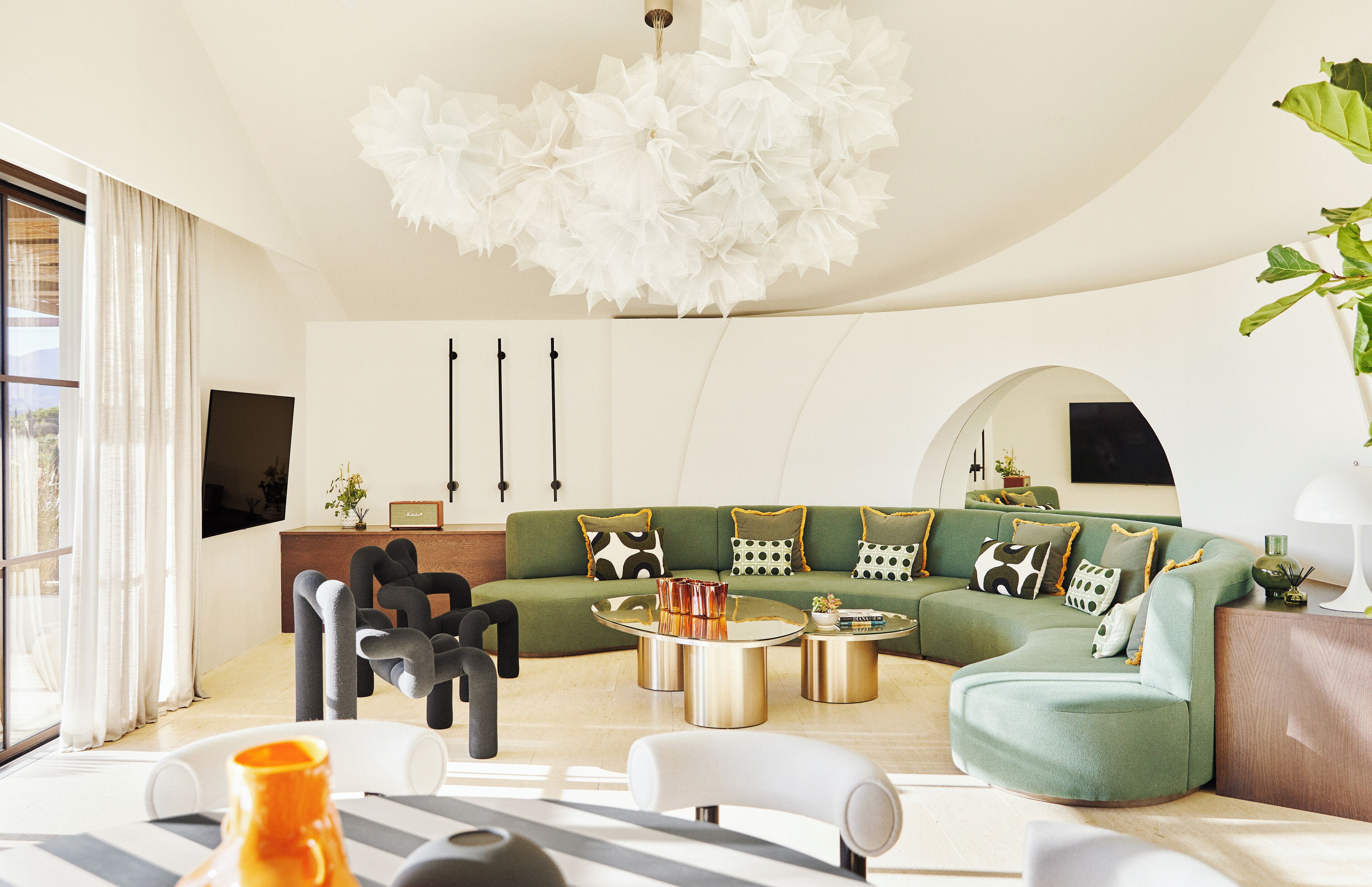 A modern living room with a green sofa, round coffee table, and a unique chandelier.