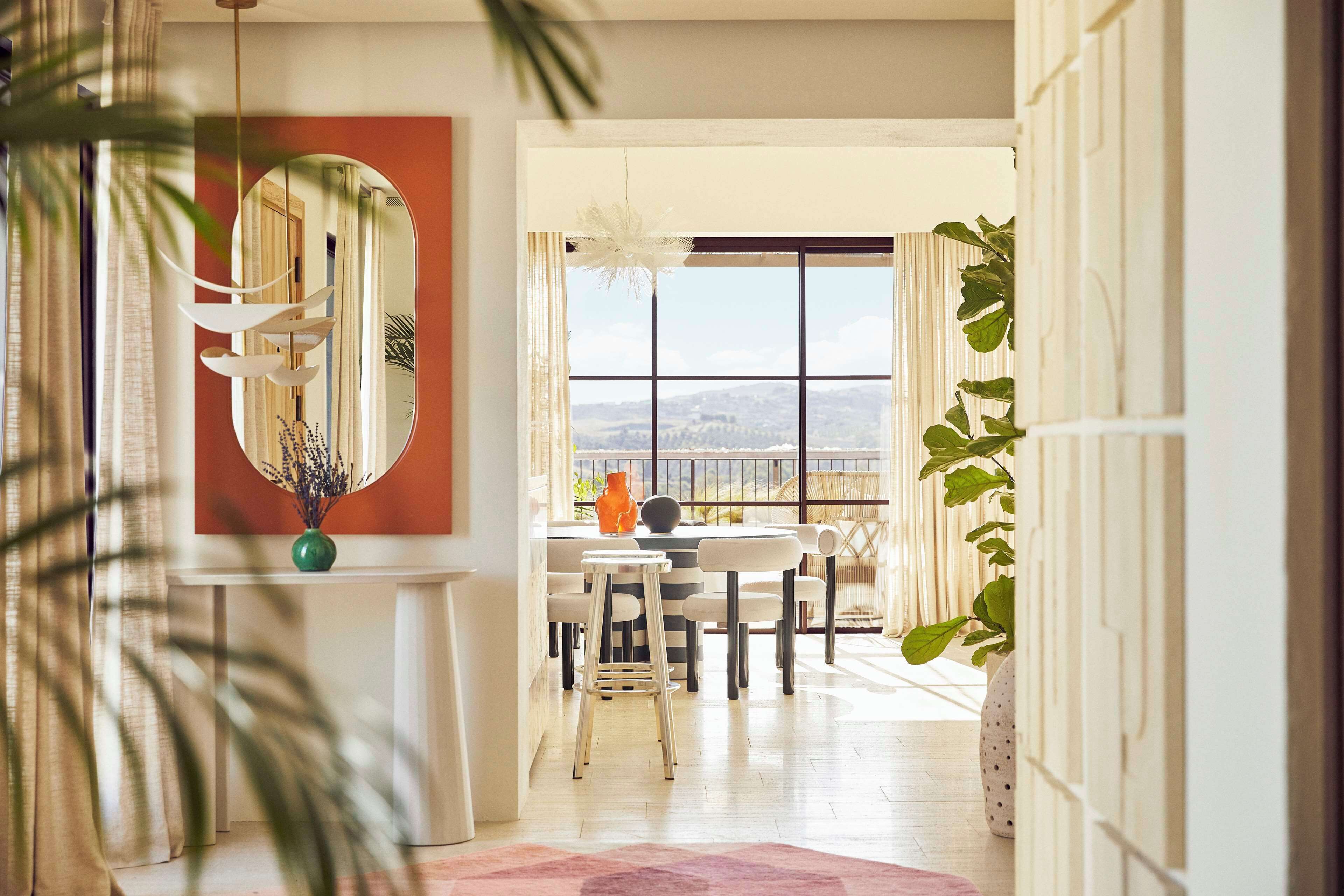 A dining area with a view of the city, a mirror, and a plant.