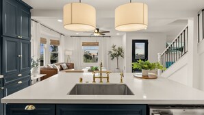 A modern kitchen with a large island, dark cabinetry, and pendant lighting. - Modern Farmhouse in the Heart of San Diego (San Diego)