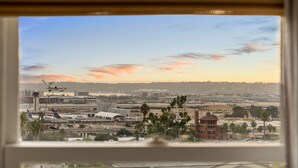 A view through a window of an airport with visible FedEx and UPS planes, airport buildings, and a distant cityscape. - Modern Farmhouse in the Heart of San Diego (San Diego)