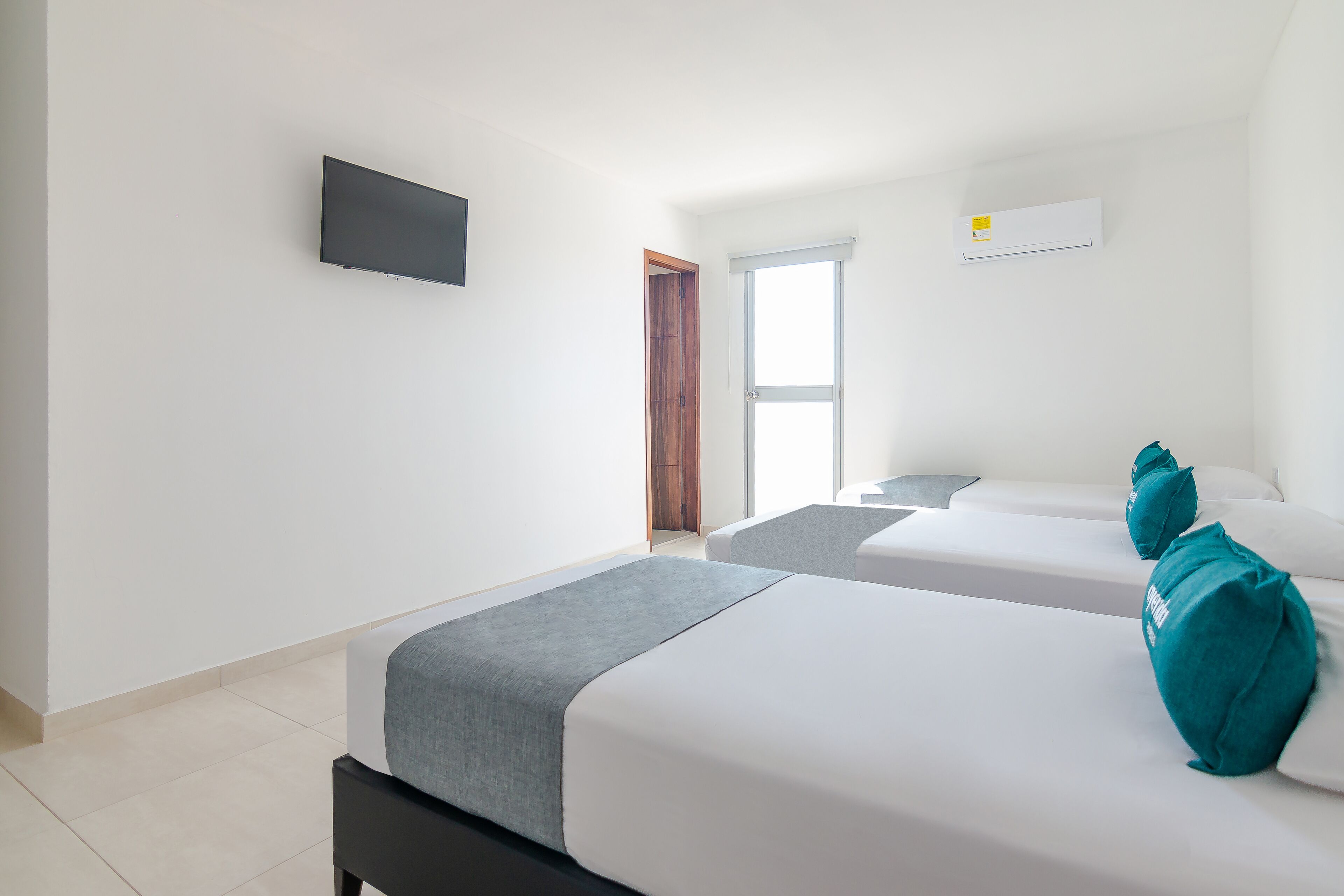 Une chambre d’hôtel avec deux lits, un téléviseur à écran plat, une fenêtre et un appareil de climatisation.