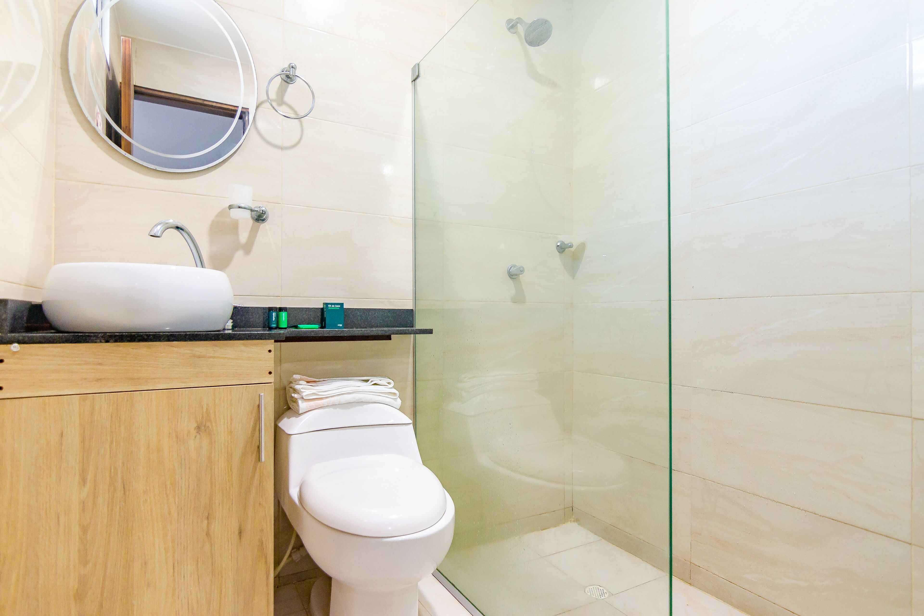 Un bagno con lavandino bianco, un water, cabina doccia in vetro e uno specchio.