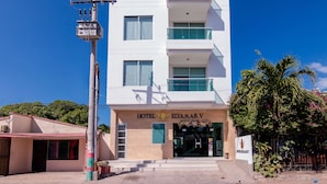 Um hotel moderno com uma placa chamativa, vários andares e céu claro.