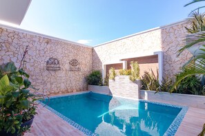 A swimming pool with stone walls and tiled edges, surrounded by potted plants and a wooden deck. - Ayenda Elyamar V (Riohacha)